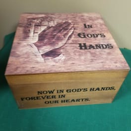 Wooden memorial box with praying hands and the words "In God's Hands"