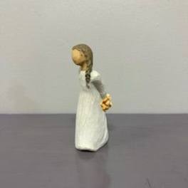 Small figurine of a girl in a white dress holding flowers behind her back