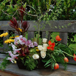 Mixed floral arrangement with orchids, roses, tulips, and yellow daisies