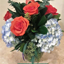 Bouquet of coral roses and pale blue hydrangeas in a glass vase