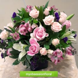 Pink roses and lilies arranged in a dark vase