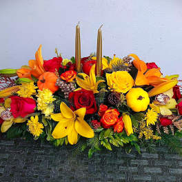 Bright floral centerpiece with roses, lilies, and candles