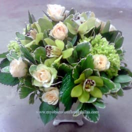 Bouquet of pale roses and green orchids in a white vase