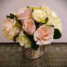 Bouquet of pale pink roses and white hydrangeas in a woven basket