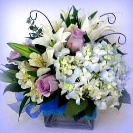 Bouquet of white lilies, pink roses, and pale hydrangeas in a vase