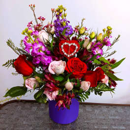 Bouquet of red and pink roses with purple flowers in a purple box