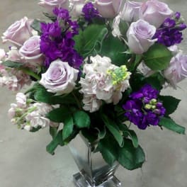 Lavender roses and purple flowers in a clear glass vase