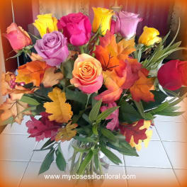 Bouquet of multicolored roses with autumn leaves in a glass vase