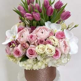 Pink tulips and roses arranged in a glittery rose-gold box