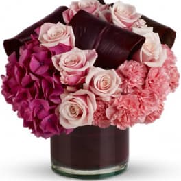Pink roses and hydrangeas arranged in a dark glass vase