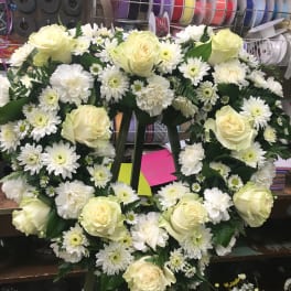 Heart-shaped floral wreath with white roses and daisies on a stand