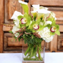 White calla lilies and orchids in a clear glass vase
