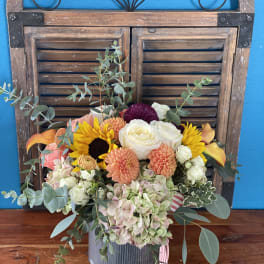 Mixed bouquet in a ribbed metal container with roses, dahlias, sunflowers, and hydrangeas