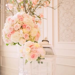 Tall pastel floral arrangement with pink roses and white blooms in a clear vase