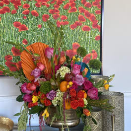 Colorful floral arrangement in a gold pedestal vase with roses and oranges