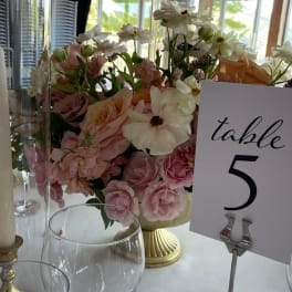 Pastel floral centerpiece in a gold vase beside a table number card