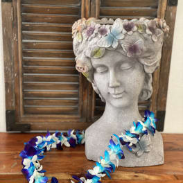 Stone bust planter with butterfly decorations and a blue-white flower lei