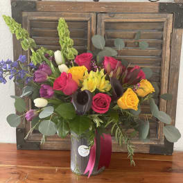 Mixed bouquet of roses, tulips, and calla lilies in a metal vase