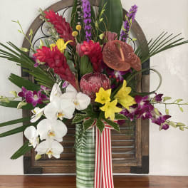 Tropical flower arrangement in a glass vase with orchids and red blooms