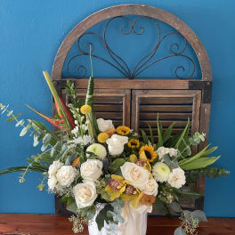 White roses and sunflowers in a white vase with greenery
