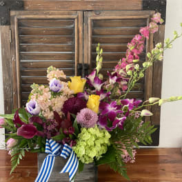 Colorful mixed flower arrangement in a wooden box with a striped ribbon