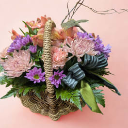 Basket of pink and purple flowers with a ribbon bow