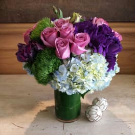 Pink roses and purple hydrangeas in a green vase with two decorative eggs
