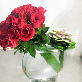Red rose bouquet with a white succulent accent in a clear glass vase