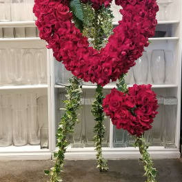 Heart-shaped floral stand with red roses and purple anthuriums