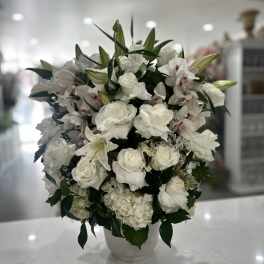 White floral arrangement in a white vase with roses and lilies