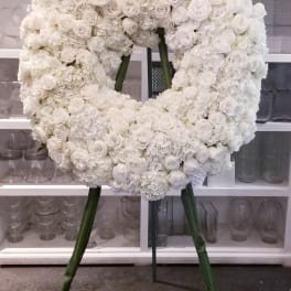 Large white floral wreath on a stand with roses and hydrangeas