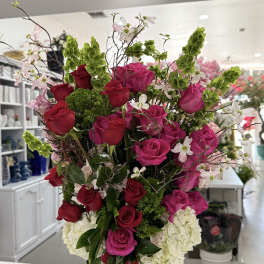 Tall bouquet of pink and red roses in a green glass vase