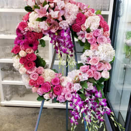 Large pink floral wreath on an easel with cascading purple orchids