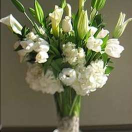 White lilies and roses arranged in a clear glass vase