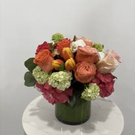 Mixed bouquet of roses, tulips, and hydrangeas in a green vase