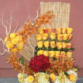 Large floral arrangement with yellow and red roses and orange orchids