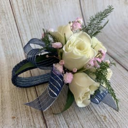 White rose corsage with pink filler flowers and blue ribbon