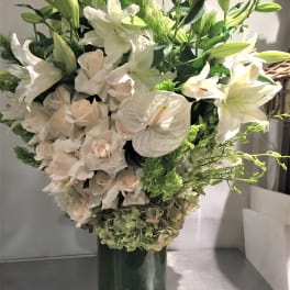 White lilies and pale roses arranged in a tall dark vase