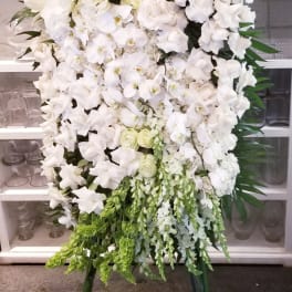 Tall white floral standing spray on an easel with green accents
