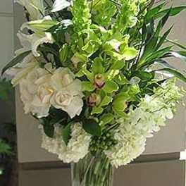 Tall white and green floral arrangement in a clear glass vase