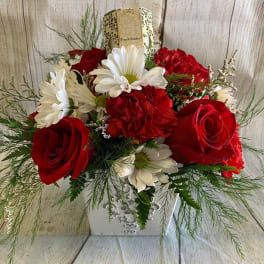 Red roses and white daisies in a decorative white container