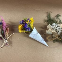 Three small dried flower bouquets on brown paper, including purple, yellow, and white arrangements