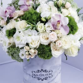 White and blush floral arrangement in a marble-print box with orchids and roses