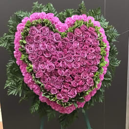 Heart-shaped pink rose funeral spray on an easel