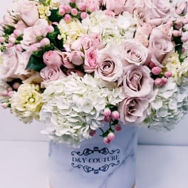 Pink and white rose arrangement in a marble-patterned hat box