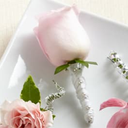 Pink rose boutonniere with white ribbon and pearl accents
