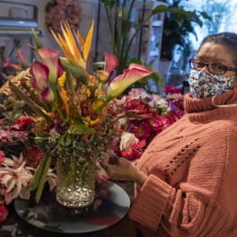 Woman holding a colorful floral arrangement in a glass vase