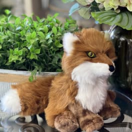Plush fox beside a potted plant and pale hydrangeas