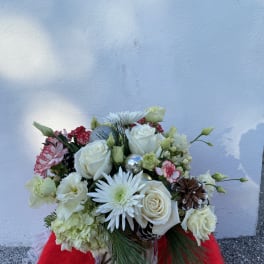 White roses and daisies in a clear vase with pinecones and silver ornaments