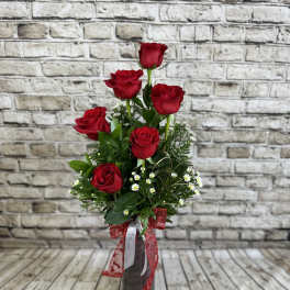 Tall bouquet of red roses in a dark vase with a red ribbon